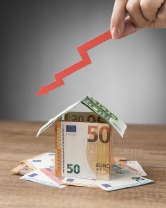 impacto do spread no valor da casa; casa feita de notas de banco representando os custos do crédito habitação