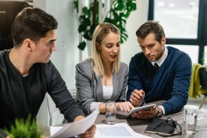 Agente imobiliário com casal jovem a analisar planos de habitação