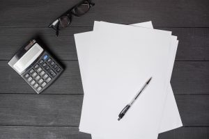 Documentos e calculadora numa mesa de trabalho imobiliário, a sugerirem, possivelmente, o cálculo do crédito habitação para jovens