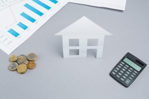 Casa em papel com moedas e gráfico de crescimento financeiro
