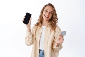 Mulher a segurar um dos seus cartões de crédito e o seu telemóvel