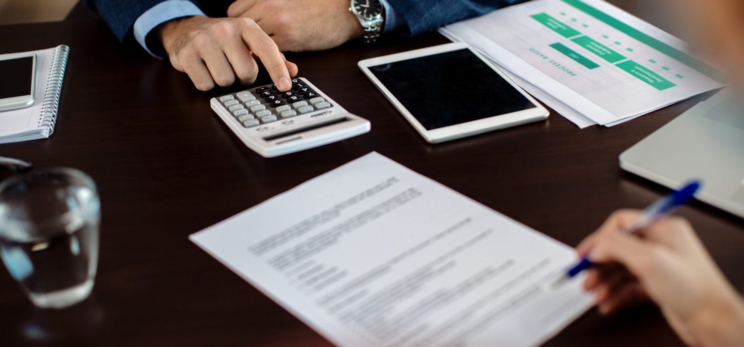 closeup-real-estate-agent-using-calculator-while-his-client-is-signing-contract