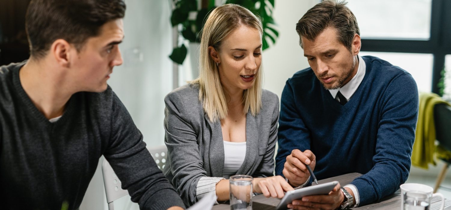 rear-estate-agent-young-couple-going-through-housing-plans-touchpad-while-having-meeting-home-1